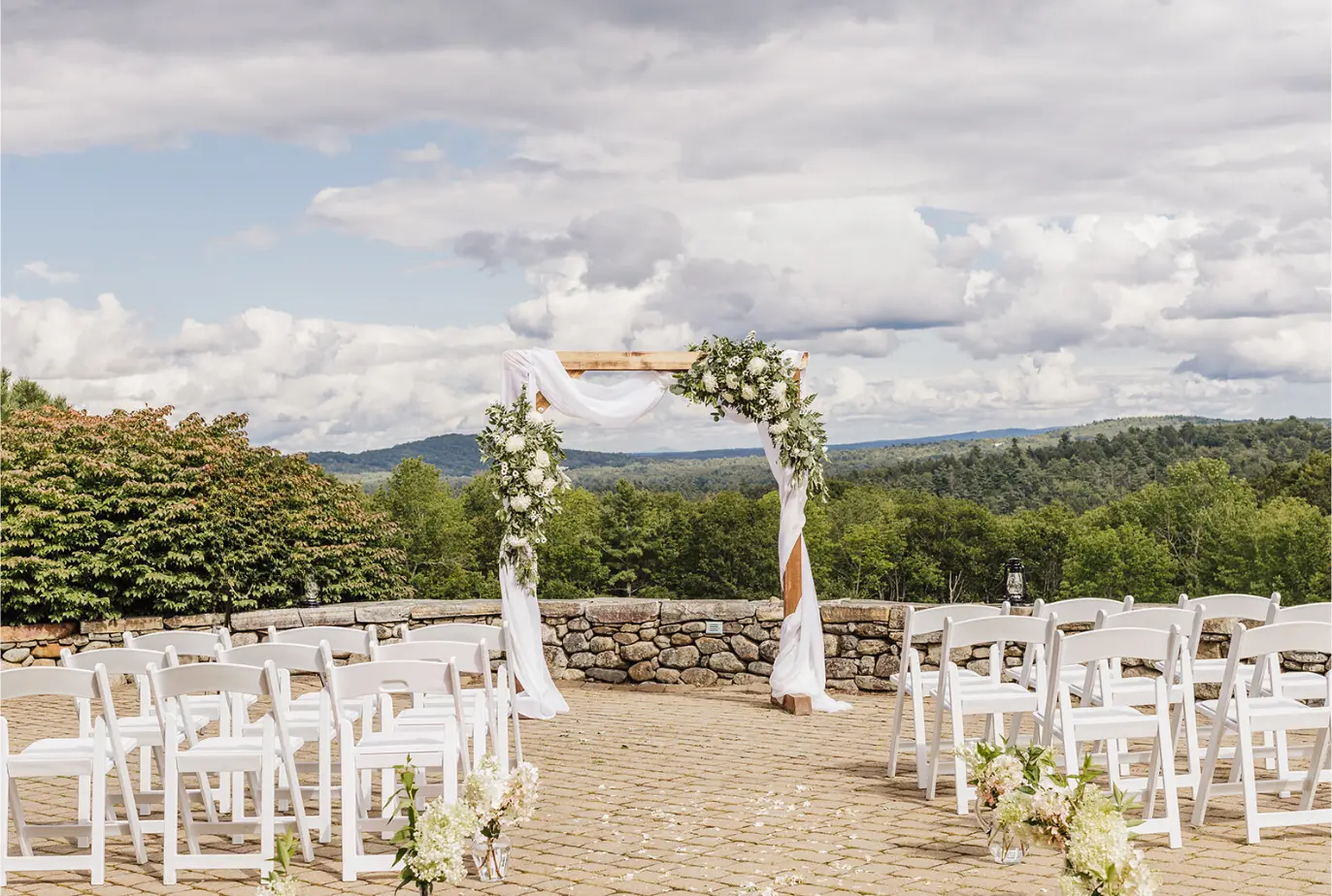 Ceremony arch and white chairs on the stone terrace overlooking the hills