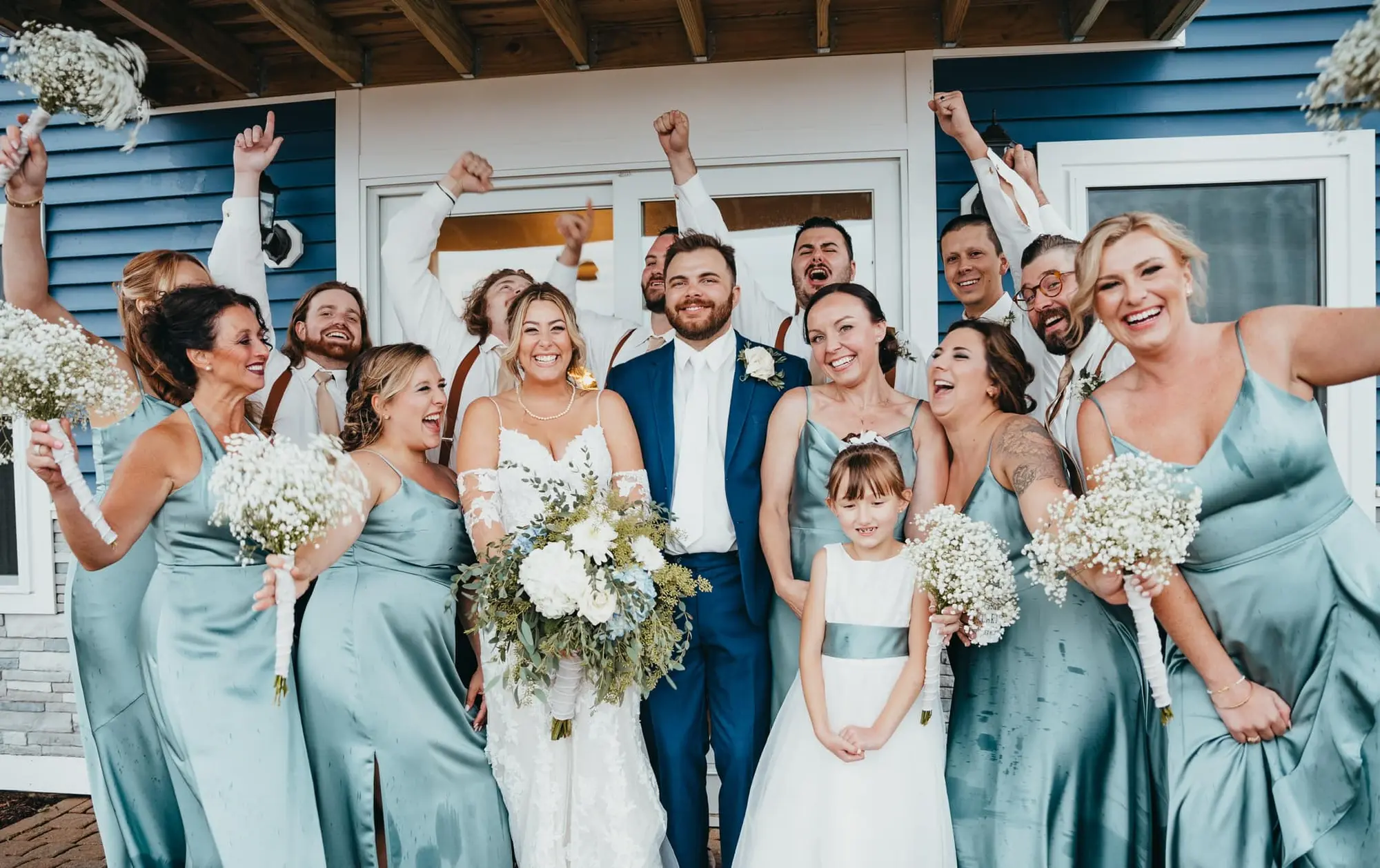 Wedding party celebrating on the front steps of the estate